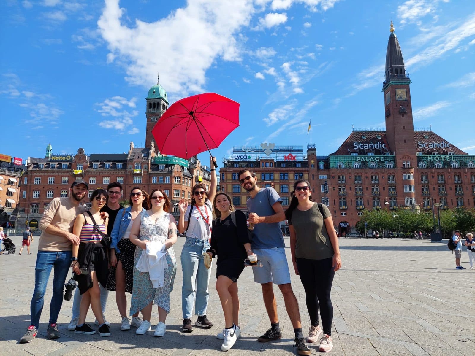 A group of travellers on a Walk and Tour free tour, under the red umbrella, at Copenhagen City Hall Square
